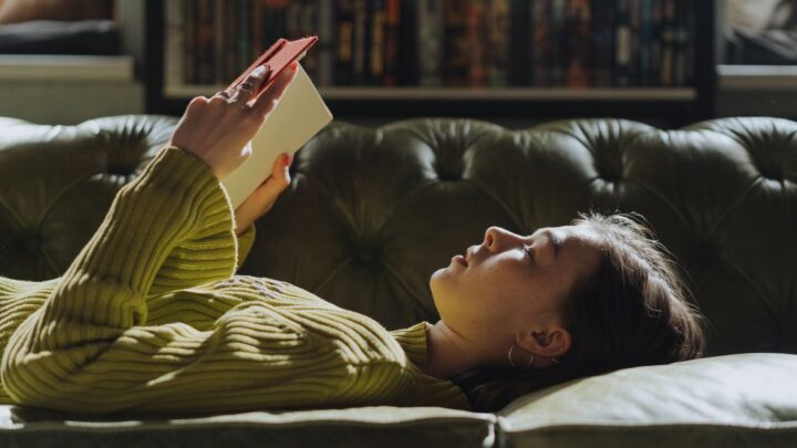 Introvert reading a book alone on a sofa, an introvert vs extrovert example