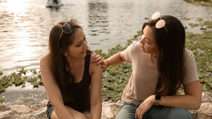 Two friends talking by a lake using questions to get to know someone