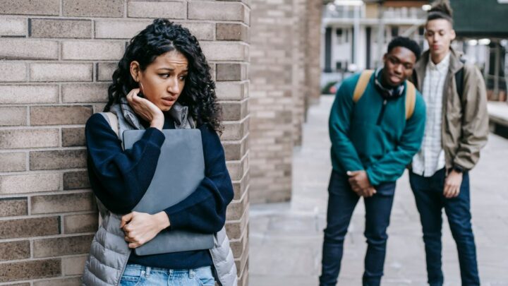 Socially awkward young woman leaning on a wall clutching a folder